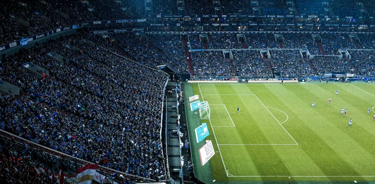 Football pitch with players and lots of fans